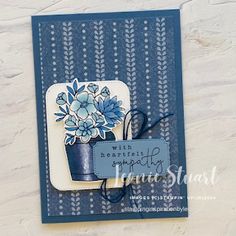 a close up of a card with a flower pot on the front and blue ribbon at the bottom