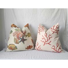 two pillows with corals and sea animals on them are sitting on a white bed