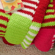 there is a crocheted blanket on the floor next to a pillow and book