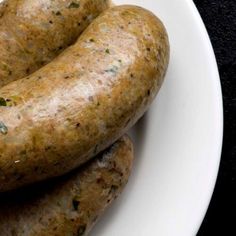 three sausages on a white plate sitting on a table