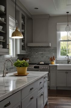 a kitchen with white cabinets and marble counter tops, an island in front of the sink