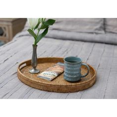 a coffee cup on a tray with a book and flower in a vase next to it