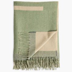 a green and beige throw with fringes on it's ends, folded in two rows