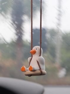 a toy penguin is sitting on a swing