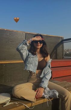 a woman sitting on top of a wooden bench next to a red heart shaped balloon