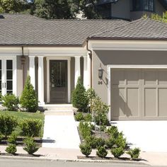 a house with two cars parked in front of it and bushes on the side of the road