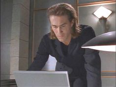 a man sitting at a table with a laptop computer in front of him and looking down