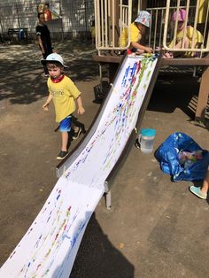 two young children playing on a slide at a playground with other kids in the background