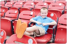 a young boy sitting in a red stadium chair