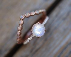 a close up of a ring with a white stone in it on a wooden surface