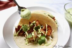 a person is spooning guacamole from a tortilla on a plate