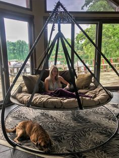 a woman sitting in a bed with a dog laying on the floor next to her