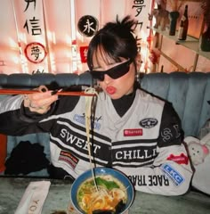 a woman eating noodles from a bowl with chopsticks