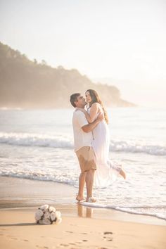 a man and woman embracing on the beach