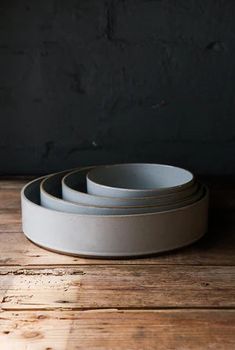 three white bowls sitting on top of a wooden table