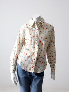 "This is a vintage floral shirt by Sears Mates from Junior Bazaar. The floral shirt features blue and red flowers. The shirt is 50% cotton and 50% polyester. CONDITION In good condition with wear consistent with age and use. Small stain spots front bust and lapel. APPROXIMATE FIT: M MEASUREMENTS Bust: 40\" .. 101.6 cm Length: 24.5\" .. 62.2 cm Shoulders: 15.5\" .. 39.7 cm Sleeve: 23\" .. 58.42 cm 72216" Classic Floral Print Button-up Top, Classic Collared Tops With Floral Print, Classic Floral Print Button-up Shirt, Classic Button-up Shirt With Floral Print, Classic Collared Top With Floral Print, Vintage Cotton Shirt With Floral Print, Classic Floral Print Spring Tops, Classic Floral Print Tops For Spring, Classic Fitted Floral Print Tops