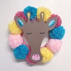 a paper cut out of a giraffe surrounded by pom - poms