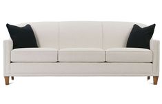 a white couch with two black pillows on the armrests and one pillow sitting on top of it