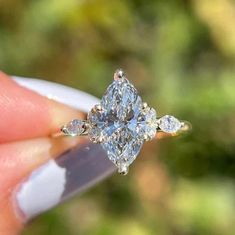 a person holding an engagement ring with three stones on it's side and the center stone in the middle