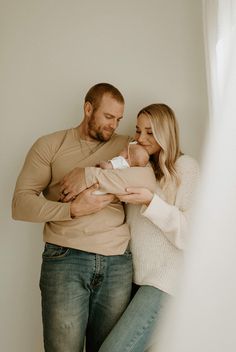 a man and woman holding a baby in their arms