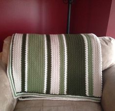 a couch with a blanket on top of it in front of a red painted wall