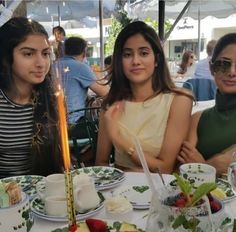 two women sitting at a table with food and drinks in front of them on plates