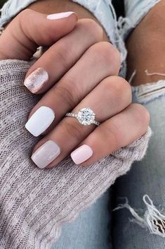 a woman's hand with pink and white manicured nails holding a diamond ring