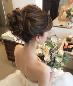 a woman in a wedding dress is looking at herself in the mirror with her bouquet