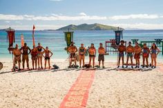 a group of people standing on top of a sandy beach next to the ocean with surfboards