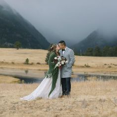 a bride and groom kissing in the mountains