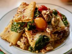 a white plate topped with pasta covered in meat and vegtables on top of it