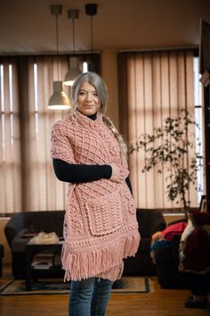 a woman standing on top of a wooden floor wearing a pink sweater and blue jeans