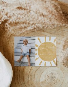 a baby's first birthday card with the sun on it is sitting on top of a piece of wood