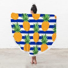 a woman is holding up a towel with pineapples on it in front of a white brick wall