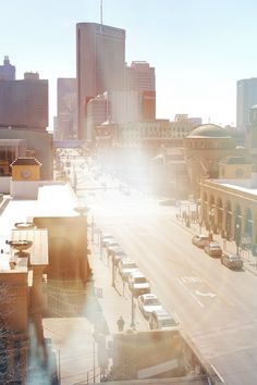 the sun shines brightly on a city street with tall buildings in the back ground