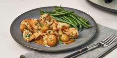 a plate full of food with green beans and meat on it next to silverware