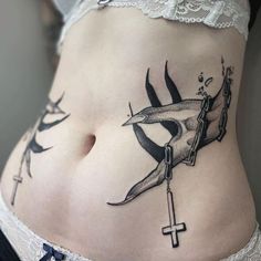 a woman's stomach with tattoos on it and a cross in the middle,