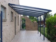 an outdoor covered walkway next to a brick building with blue trim on the top and bottom