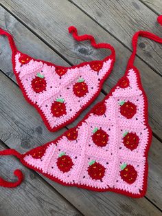 two crocheted red and pink items sitting on top of a wooden floor