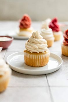 several cupcakes with white frosting on a plate