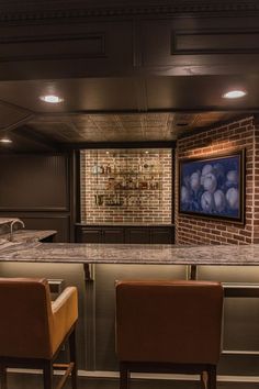 two brown chairs sitting in front of a bar with a tv on it's wall