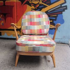 a colorful chair sitting in front of a wall with graffiti on it's side