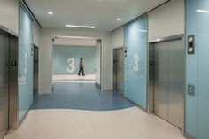 an empty hallway with blue and white flooring, two elevators on either side of the room