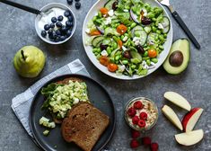 a table topped with plates of food next to fruit and veggie salads