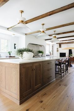 a large kitchen with wooden floors and white walls, has an island in the middle