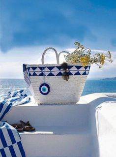 a blue and white basket sitting on the side of a boat with flowers in it