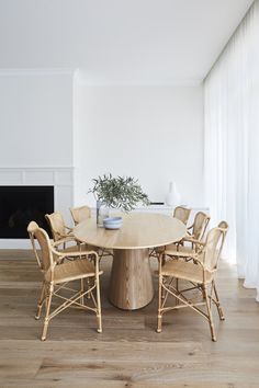 a dining room table with chairs and a potted plant in the center on top