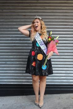 a woman in a black dress is holding flowers and posing for the camera with her hand on her head