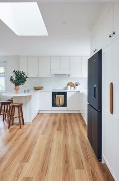 an open kitchen with white cabinets and wood flooring is seen in this image from the doorway