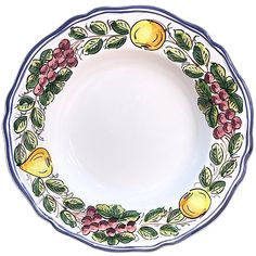 a white plate with fruit and leaves painted on the rim, sitting in front of a white background